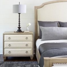 a bedroom with a bed, nightstand and lamp on the end table in front of it