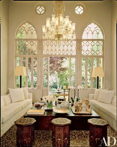 a living room filled with furniture and a chandelier hanging over the top of it