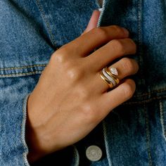 a woman's hand with two rings on her finger, wearing a denim jacket