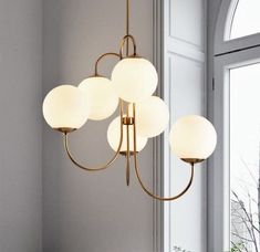 a chandelier hanging from the ceiling in a dining room with white walls and windows