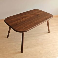 a wooden table sitting on top of a hard wood floor next to a white wall