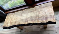 a wooden bench sitting in front of a window on top of a hard wood floor