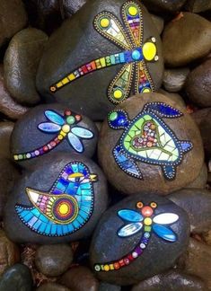 some rocks with painted designs on them and some stones in the shape of dragonflies