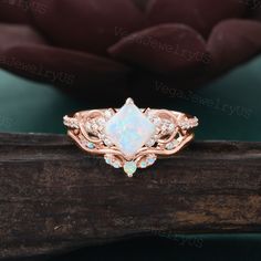 an opal and diamond ring sits on top of a piece of wood