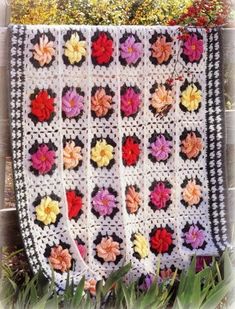 a crocheted granny's afghan with flowers on it sitting in the grass