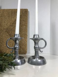 two silver candles sitting on top of a table