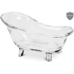 a clear glass bath tub sitting on top of a white table next to a gold seal