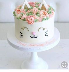 a white cake decorated with pink roses and cat ears