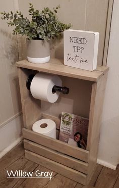 a toilet paper dispenser next to a wooden shelf with books and magazines on it