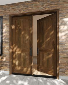 two wooden doors are open in front of a brick wall and stone floored area