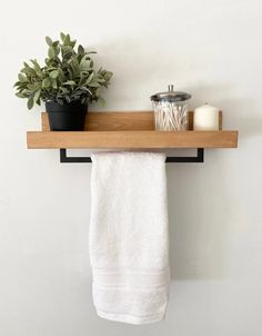 a towel hanging on a wooden shelf next to a potted plant and candle holder