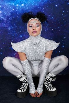 a woman in white is sitting on the ground with her legs crossed and wearing silver shoes