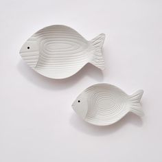 two white fish shaped dishes sitting on top of each other