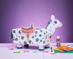 a wooden toy cow sitting on top of a table next to some crafting supplies