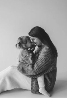 two women are sitting on the floor with their arms around each other and one is holding a baby