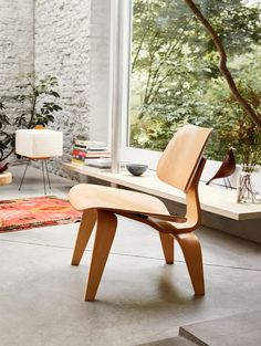 a wooden chair sitting in front of a window next to a table with books on it