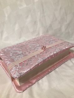 a pink book with a bow on it sitting on a white cloth covered tablecloth