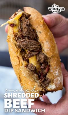 a hand holding a sandwich with meat and cheese on it that says shredded beef dip sandwich