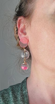 a close up of a person wearing earring with pink and clear beads on them