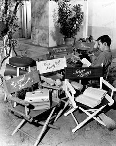 a man sitting in a chair with many signs on it's back and one reading a book