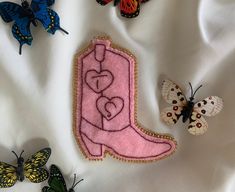 some butterflies are laying on top of a white sheet and there is a pink boot with a heart in the middle