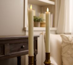 two white candles sitting on top of a table