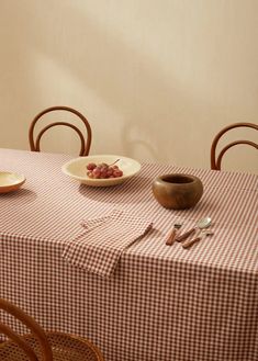 the table is set with two plates and one bowl of fruit on top of it