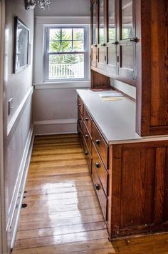 a kitchen with wooden cabinets and white counter tops in front of a window on the wall