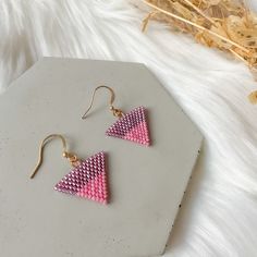 pink and gold triangle earrings on white furnishing