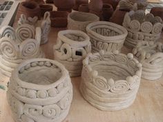 several clay pots sitting on top of a wooden table next to other pottery containers and vases