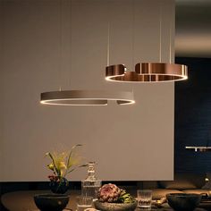 a dining room table with plates and bowls on it, lights hanging from the ceiling