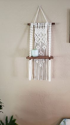 a macrame hanging on a wall next to a potted plant