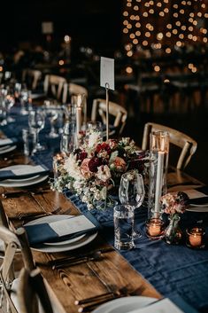 a table set with place settings, candles and flowers on it for an elegant dinner