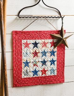 a red, white and blue quilt hanging on a wall next to a baseball bat