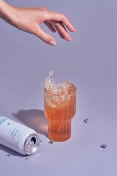 a hand reaching for an ice tea in front of a can of soda and confetti