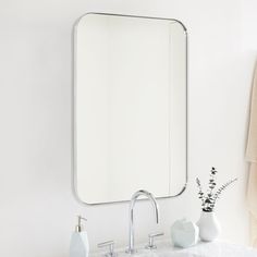 a bathroom sink with a mirror above it and two vases on the counter next to it