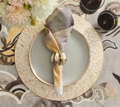 a place setting with napkins, silverware and flowers on the tablecloth is ready to be served