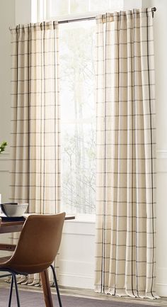 a dining room with a table and chairs next to a window covered in beige curtains