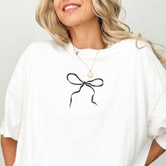 Indulge your love for all things charming with our bow coquette shirt, radiating vintage-inspired allure and a playful coquette aesthetic! Perfect for those who adore girly oversized graphic tees! ✨ Product Details (Gildan 5000) ✨ 100% Preshunk Cotton Medium Weight Fabric, Minimal Stretch (5.3 oz/yd² (180 g/m Tear away neck label  Runs true to size, order 2-3 sizes up for an oversized fit  Size Measurements - Lay garment flat. Width is measured 1" below the armhole flat across the chest. Body length is measured on center back line seam - from top of shirt to the bottom. Small (Length - 28", Width 18") Medium (Length - 29", Width - 20") Large (Length - 30", Width - 22") X-Large (Length - 31", Width - 24") 2X-Large (Length - 32", Width - 26") 3X-Large (Length - 33", Width - 28") 4X-Large (Le Trendy White Top With Bow, Black Vintage Top Gift, Vintage Black Top Gift, Vintage Black Top As Gift, Trendy White Tops With Bow Print, Trendy White Top With Bow Print, Girly Shirts, Ribbon Shirts, Oversize Tshirt Outfits