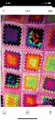 a pink crocheted blanket with squares and hearts on the bottom, in different colors