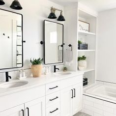 a white bathroom with two sinks, mirrors and bathtub in the middle is shown