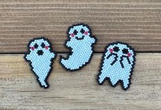 three pixellated ghost pins sitting on top of a wooden table