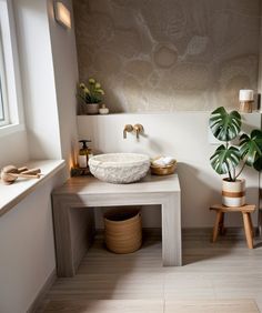 a white sink sitting under a window next to a potted plant in a bathroom