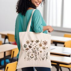 🌿 Embrace nature's charm with our Canvas Tote Bag, featuring an exquisite wildflower design. Unique wildflowers rendered in beautiful earthy tones.  🌸 This tote is not just a bag; it's a piece of art, perfect for adding a touch of boho elegance to your everyday style. 👜 Made from 100% cotton, this durable tote measures 15''x16'', offering ample space for your essentials. Whether you're heading to the farmer's market, a day out with friends, or packing for a quick getaway, this bag is your go-to choice for both style and practicality. 💐 Ideal for bridal parties and bachelorette events, it adds a personalized and thoughtful touch. Surprise your bridesmaids with this unique gift that they can use long after your special day. It's not just a bag; it's a keepsake. 🎁 Perfect for any woman w Green Nature-inspired Bag For Everyday Use, Nature-inspired Green Bags For Everyday Use, Eco-friendly Rectangular Bag With Floral Print, Green Floral Print Bags As Gifts, Green Floral Print Bags For Gifts, Green Floral Print Bags Suitable For Gifts, Green Floral Print Bags Ideal For Gifts, Eco-friendly Flower-shaped Shoulder Bag For Everyday Use, Eco-friendly Flower Shaped Shoulder Bag For Everyday Use