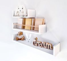 two white shelves with books and stuffed animals on them, one is reading the word dream