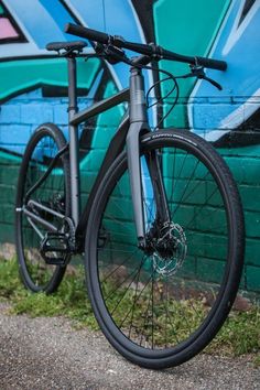 a bicycle parked in front of a wall with graffiti on it's walls and grass