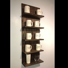 a wooden shelf with coffee mugs and glasses on it, mounted to the wall