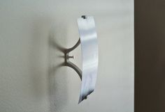 a white wall with a metal hook on it's side and an object in the background