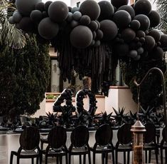 black balloons are hanging from the ceiling above tables and chairs in front of a building