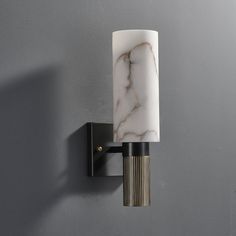 a wall light that is mounted to the side of a wall with a marbled glass shade